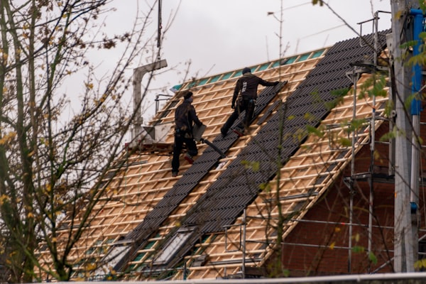 Workers installing shingles on a residential roof